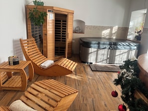 A sauna room with wooden benches, a massage table, and a steam room.