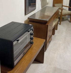 A kitchenette with a black oven, wooden drawers, and a tiled floor. - شاليه عائلي فاخر في AquaView أكوافيو (elhammam)