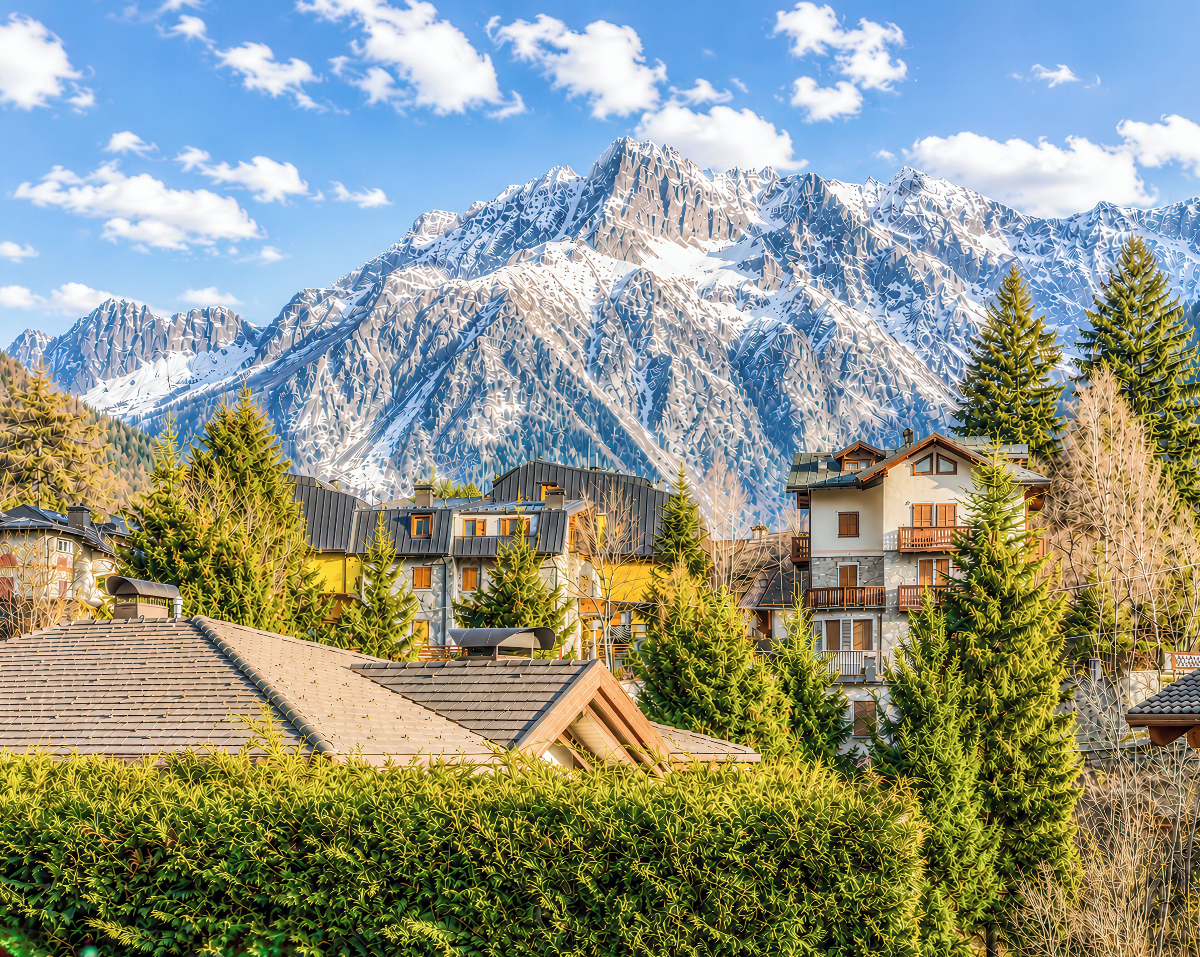 A mountain village with traditional houses, a clear sky, and snow-capped mountains in the background.
