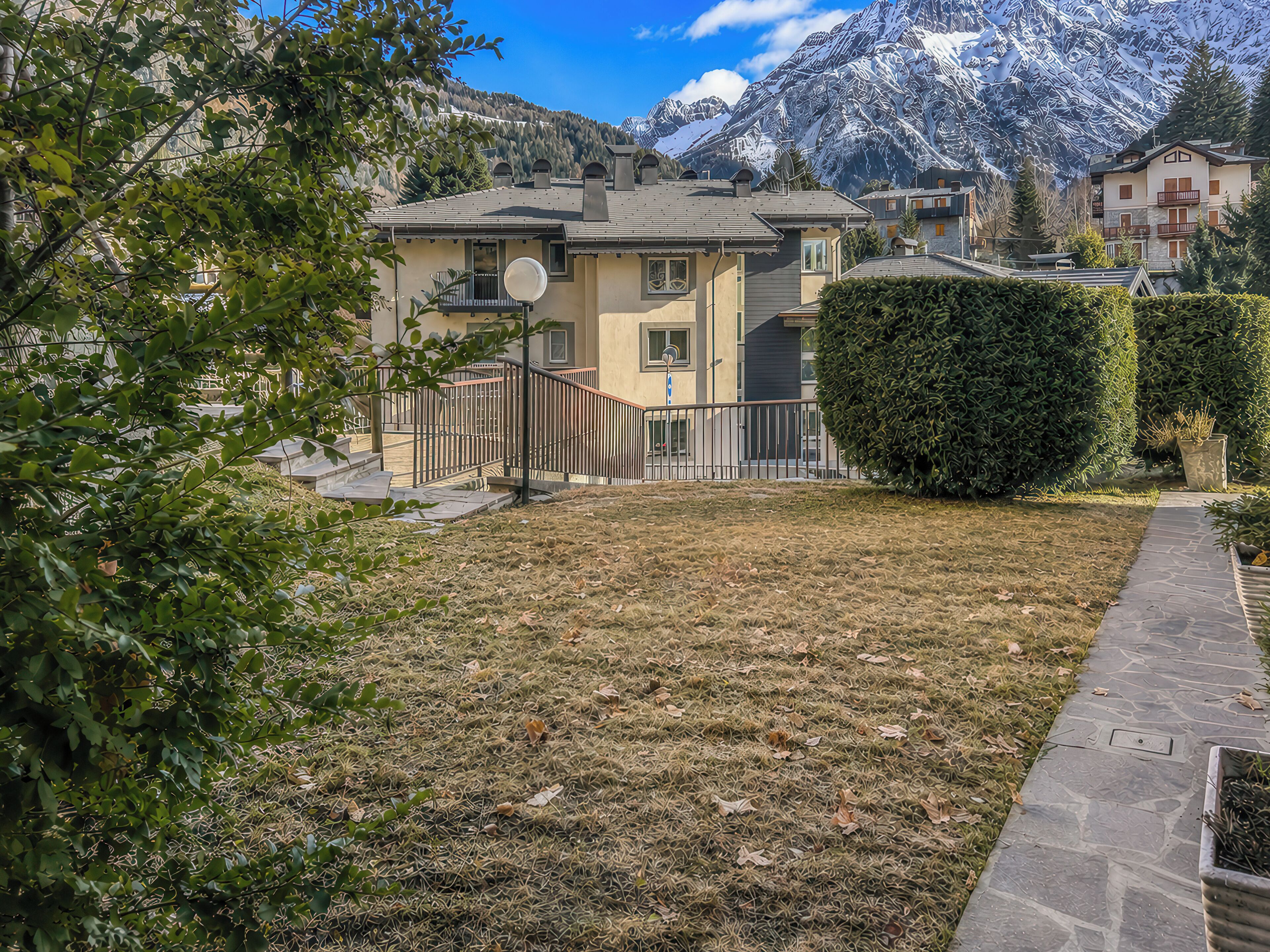 A residential area with a house, a stone pathway, and a mountain backdrop.