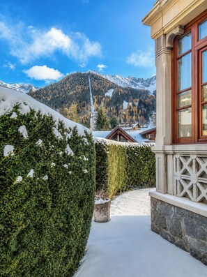 Ein verschneiter Weg, der zu einem Gebäude mit Blick auf die Berge führt.