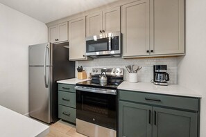 Una cocina moderna con electrodomésticos de acero inoxidable, microondas, hervidor de agua y cafetera.