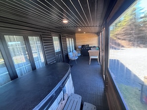 A covered outdoor area with a counter, chairs, and a grill.