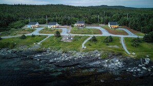 A cluster of houses with a winding road, surrounded by forest and a rocky shoreline. - Oceanfront Boutique Retreat~Hot Tub~Woodstove (Hearts Delight-Islington)