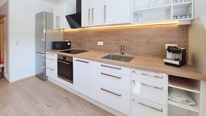 Una cocina moderna con armarios blancos, una campana extractora negra, un microondas integrado, un fregadero y una cafetera.