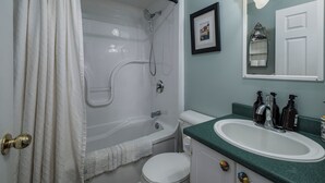 A bathroom with a bathtub, toilet, sink, and a framed picture on the wall.