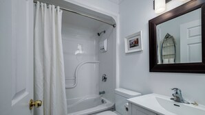 A bathroom with a bathtub, toilet, sink, and a mirror.