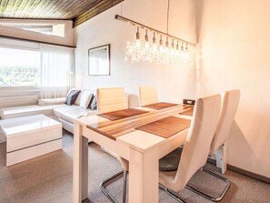 Un salon moderne comprenant un coin repas, un canapé, une table basse et un lustre.