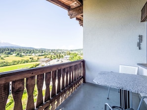 A balcony with a wooden railing, a table, and a chair.