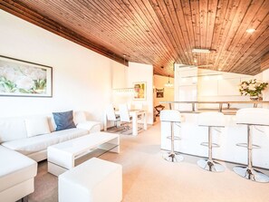 Ein modernes Interieur mit Holzbalkendecke, weißen Möbeln, einem Essbereich und einer Küche.