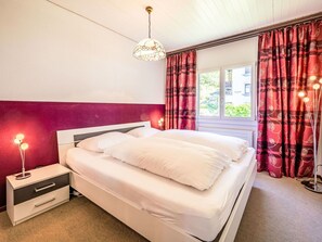 Une chambre à coucher avec un lit, une lampe de chevet et des rideaux.