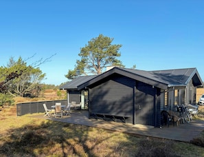 Eine Hütte mit Terrasse, Sitzgelegenheit im Freien und Fahrrädern.