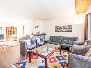 Ein Wohnzimmer mit einer Couch, zwei Sesseln, einem Couchtisch, einer Kommode und einem Gemälde an der Wand.