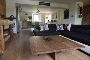 Un soggiorno moderno con un tavolino in legno, un divano nero e cuscini decorativi.