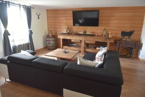 A living room with a black sofa, wooden coffee table, and a mounted television. - Renovated farmhouse from 1791 with a hot tub; pets welcome; near Alsace (Provenchères-et-Colroy)