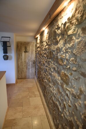 A hallway with a stone wall, wooden door, and a light fixture. - Renovated farmhouse from 1791 with a hot tub; pets welcome; near Alsace (Provenchères-et-Colroy)