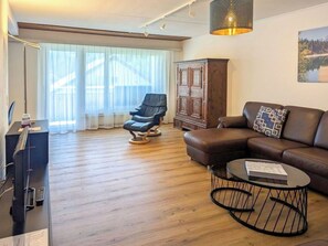 A modern living room with a leather sofa, a black armchair, a wooden cabinet, and a round coffee table. - Lovely apartment for 8 guests with WIFI, TV and balcony (Laax)