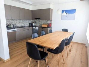 Eine moderne Küche mit grauen Schränken, einem Holztisch und schwarzen Stühlen.
