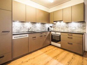 Eine moderne Küche mit Holzausstattung, einem Geschirrspüler und einem Backofen.