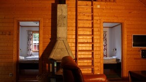 L’intérieur d’un chalet en bois comprend une cheminée, un canapé et deux chambres.