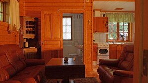 Un intérieur de chalet chaleureux comprenant un salon, un coin repas et une cuisine.