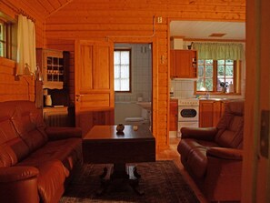 Ein gemütliches Blockhaus-Interieur mit Wohnbereich, Essplatz und Küche.