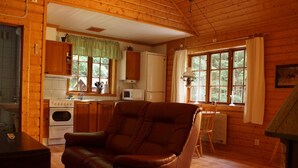 L’intérieur d’un chalet en bois comprend une cuisine, un fauteuil en cuir et une table à manger.