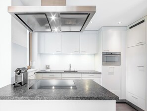 Eine moderne Küche mit Granit Arbeitsplatte, Edelstahlgeräten und weißen Schränken.
