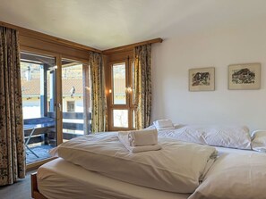 Ein Hotelzimmer mit Bett, Blick durch eine Glastür und zwei gerahmten Bildern an der Wand.