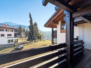 Ein Balkon mit Blick auf eine Berglandschaft, Holzgeländern und einem klaren Himmel.