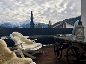 Eine Terrasse mit Tisch und Stühlen, einer Laterne und Blick auf schneebedeckte Berge.