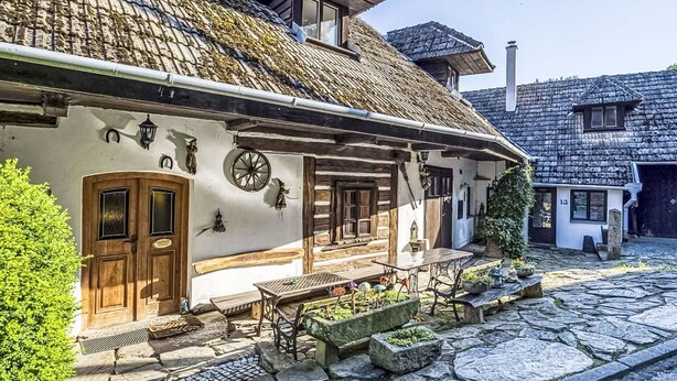 En traditionell byggnad med en fasad av sten, trädörrar och en innergård med kullerstenar.