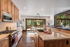 A spacious kitchen with wooden cabinets, a large island, and a view of the outdoors. - Private Ski-out Village Home in Vail with Hot Tub (Vail)