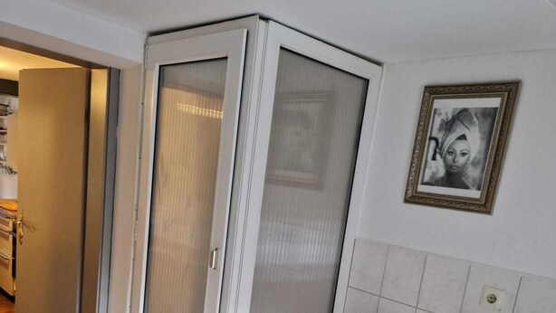 A room with a sliding glass door, a white chair, a wicker basket, and a framed picture on the wall. - Cozy attic apartment with garden access (Burg Stargard)