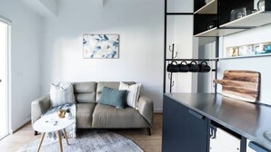 A modern living room with a sofa, a coffee table, and a painting on the wall. - Warrina Nook A Cosy Bushland Escape for Two (Chatswood West)