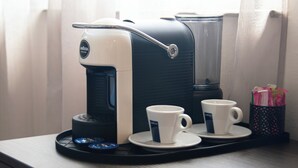 A coffee maker with two cups on a tray, a coffee pot, and a container with pens. - Mostay Boutique Hotel (Mostar)
