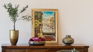 A dining area with a wooden cabinet, a painting, and chairs. - Mostay Boutique Hotel (Mostar)