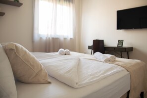 A hotel room with a bed, pillows, a desk, a chair, and a flat-screen TV mounted on the wall. - Mostay Boutique Hotel (Mostar)