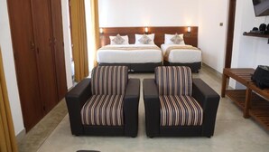 A hotel room with two beds, a sofa, a TV, and a wardrobe. - Ceylon Ayu Resort - Kandy (Kandy)
