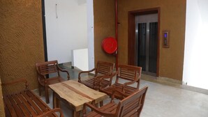 A room with a wooden table and chairs, a red fire hose, a door with a metal handle, and a wall-mounted light switch. - Ceylon Ayu Resort - Kandy (Kandy)