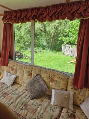 A room with a sofa facing a large window, a view of a grassy yard, and a wooden fence.
