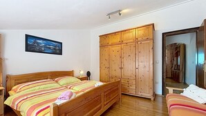 Een slaapkamer met een houten bed, een kledingkast en een schilderij aan de muur.