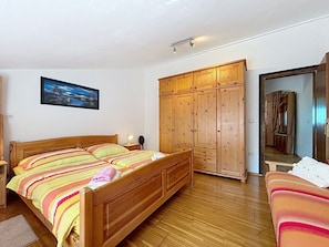 Ein Schlafzimmer mit einem Holzbett, einem Kleiderschrank und einem Gemälde an der Wand.