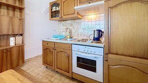 Een keuken met houten kastjes, een fornuis en een betegelde achterwand.