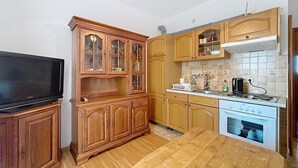 Eine kleine Küche mit Holzausstattung, einem Einbauofen und einem Fernseher auf einem Holzständer.