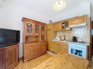 Eine kleine Küche mit Holzausstattung, einem Einbauofen und einem Fernseher auf einem Holzständer.