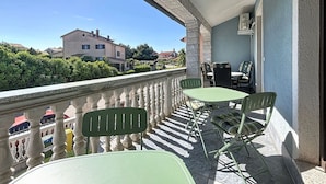 Ein Balkon mit Steinbalustrade, einem Tisch und zwei Stühlen.