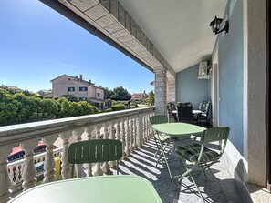 Ein Balkon mit Steinbalustrade, einem Tisch und zwei Stühlen.