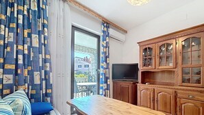 Ein Zimmer mit einer Couch, einem Holztisch, einem Fernseher und Holzschränken.