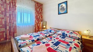 A bedroom with two beds, a window with curtains, a wall-mounted picture, and a bedside lamp. - Cosy apartment for 2 guests with A/C, WIFI and TV (Banjole)